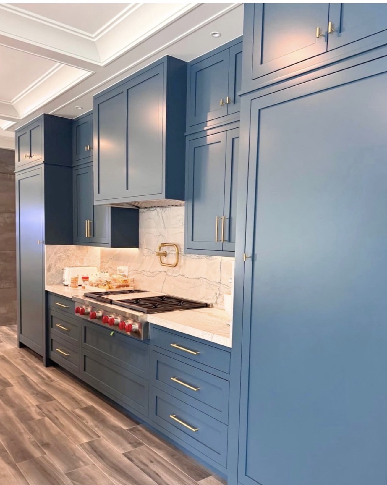 Navy kitchen with marble backsplash, gold faucet and professional range — St. Louis remodel by Phoenix Construction Group