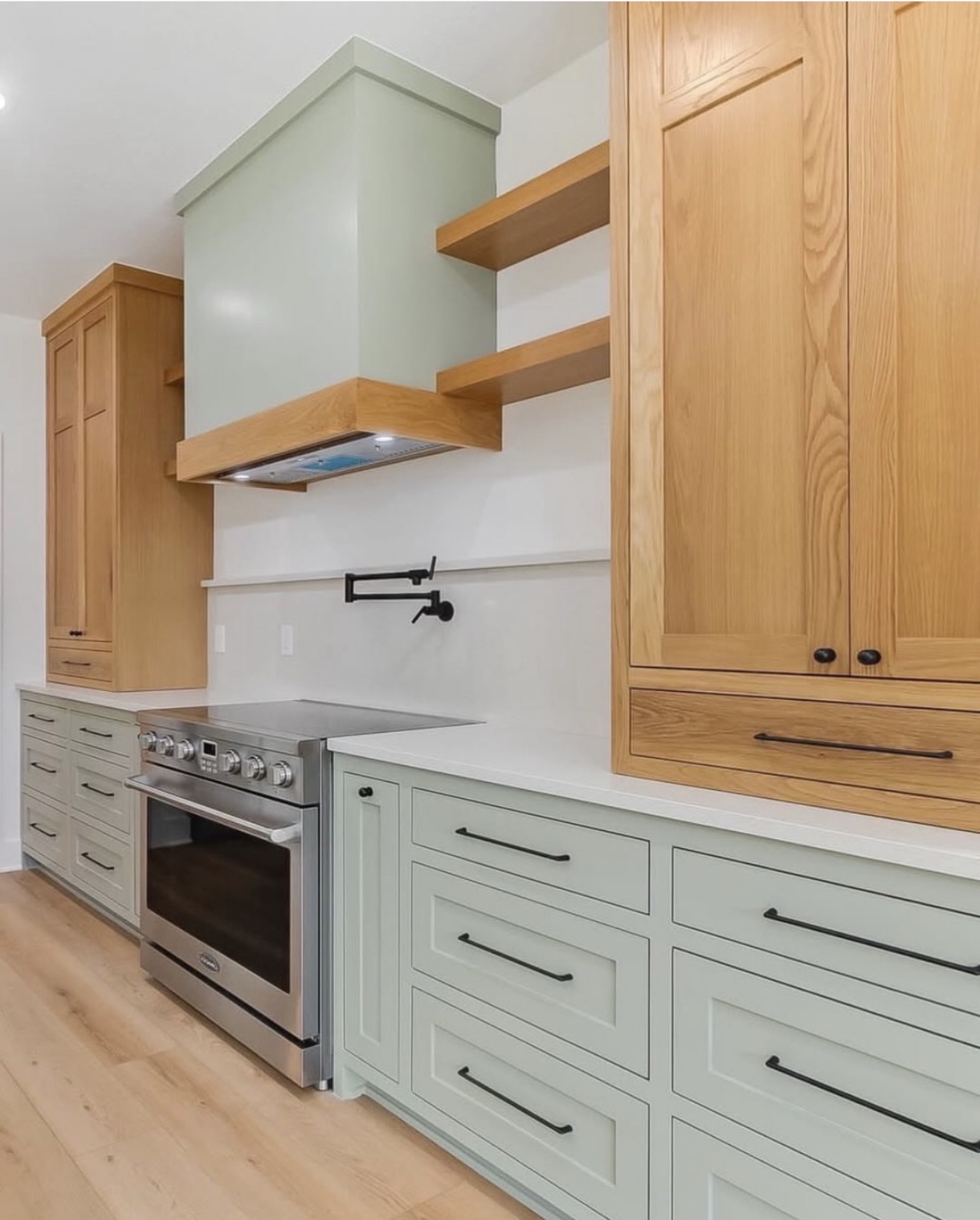 Sage green modern farmhouse kitchen with open wood shelving and professional range — St. Louis remodel by Phoenix Construction Group