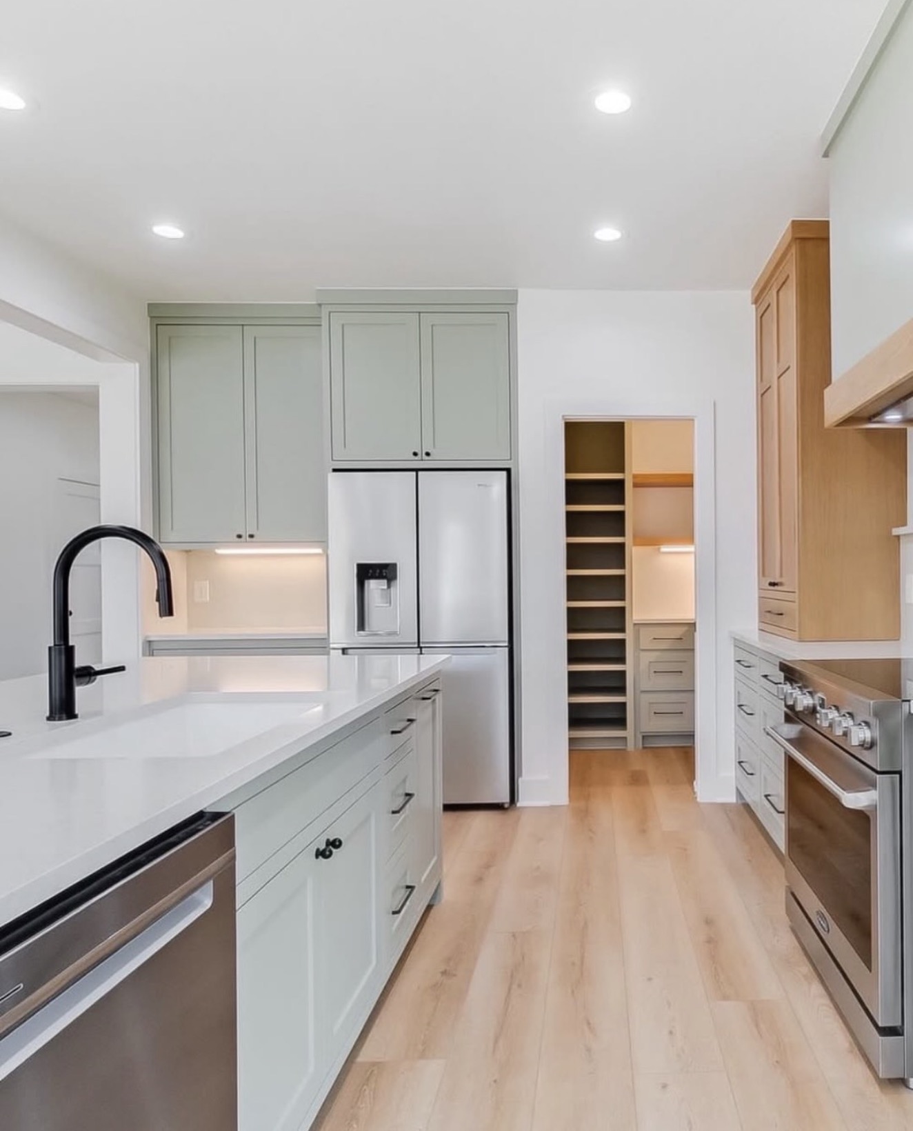Sage green kitchen with walk-in pantry and matte black faucet — St. Louis remodel by Phoenix Construction Group