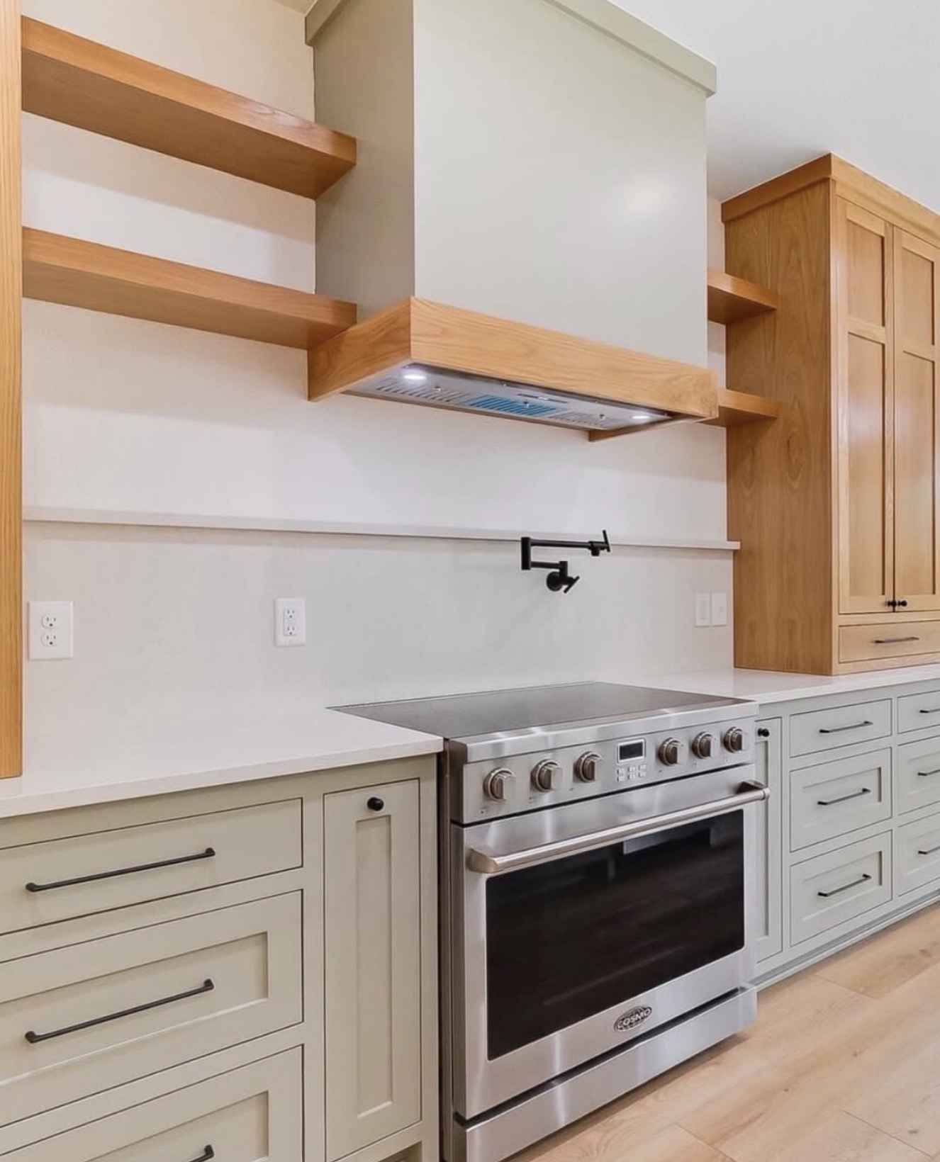 Sage green kitchen with open wood shelves and pot filler — St. Louis remodel by Phoenix Construction Group